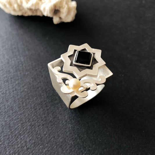 Handmade silver statement ring with geometric star design, square black onyx centerpiece, freshwater pearl accent, and oxidized details.