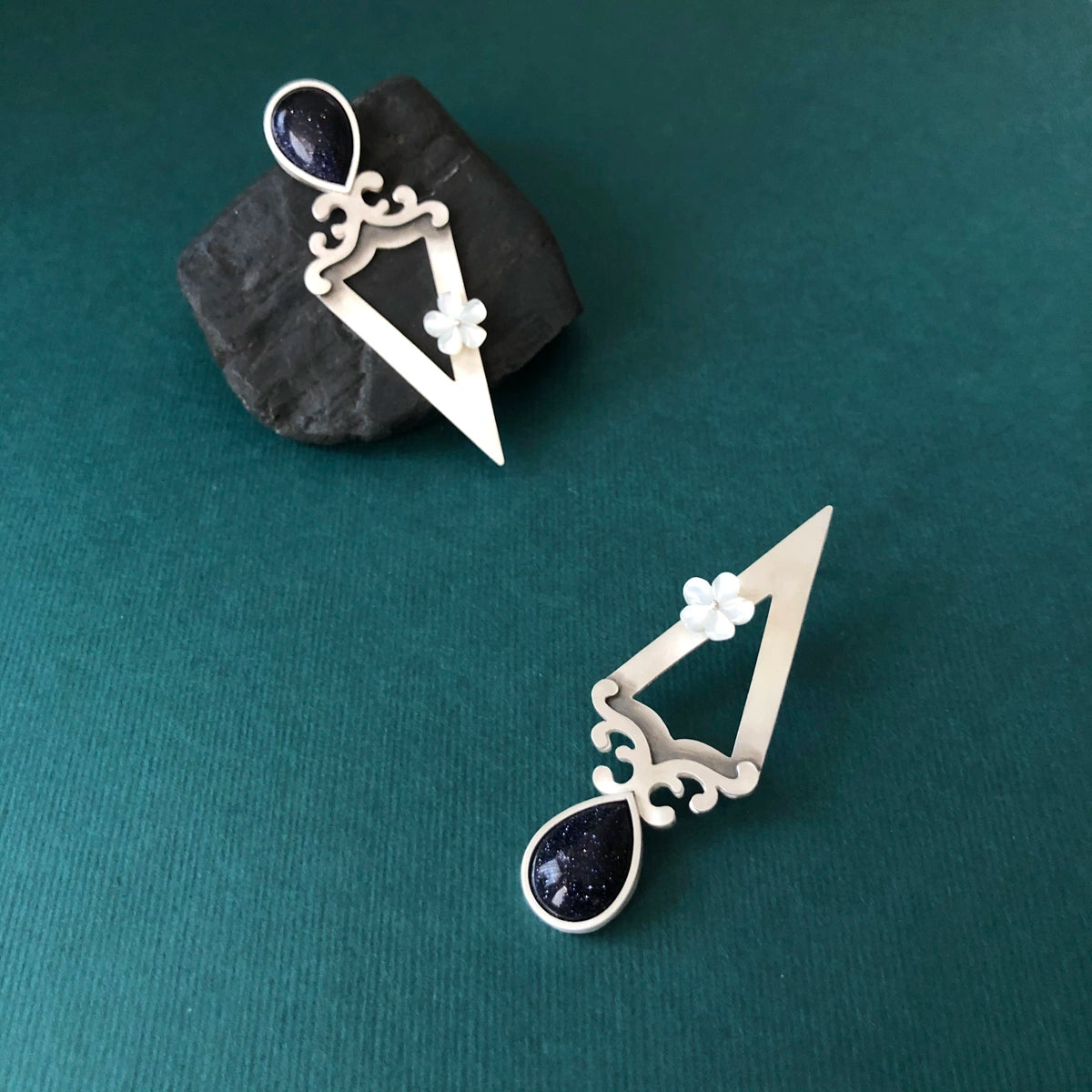 triangular earrings decorated with floral motifs, mother of pearl flower and blue star gemstone. 