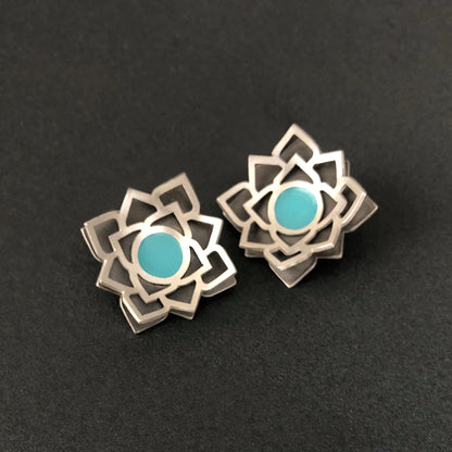 Handmade sterling silver lotus stud earrings with layered openwork design, oxidized silver base, and turquoise-blue enamel centerpiece.