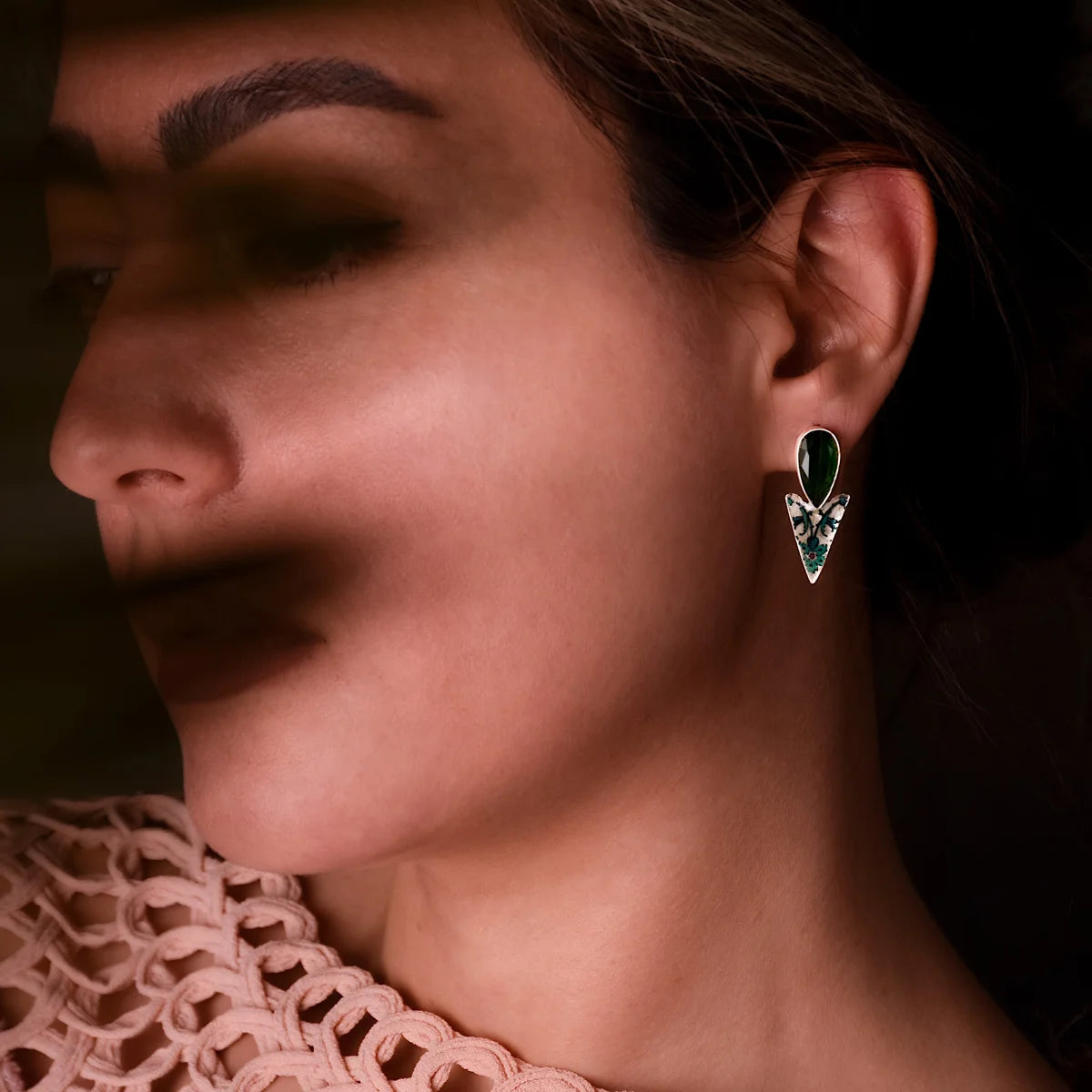 model wearing handcrafted mismatched silver earrings with green floral patterns and green cubic zirconia