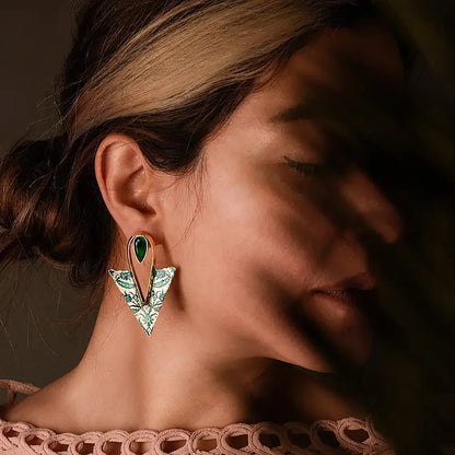 model wearing handcrafted mismatched silver earrings with green floral patterns and green cubic zirconia