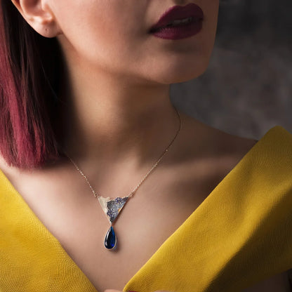 woman wearing handmade silver pendant necklace with blue cubic zirconia and blue floral patterns