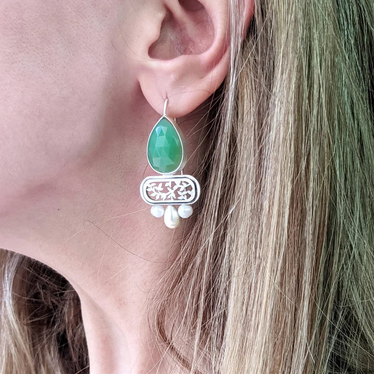 woman wearing handmade statement drop silver earrings with faceted green onyx and pearls