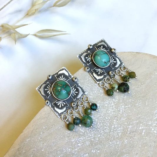 handcrafted oxidized silver stud earrings decorated with turquoise gemstones and floral motifs.